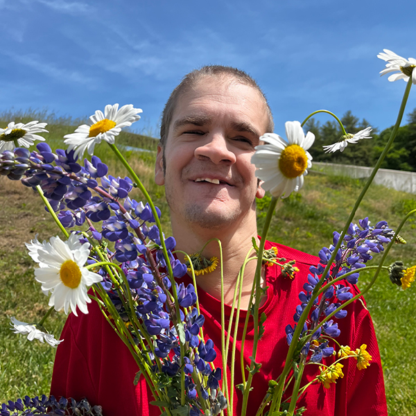 man standing in a field holding flowers